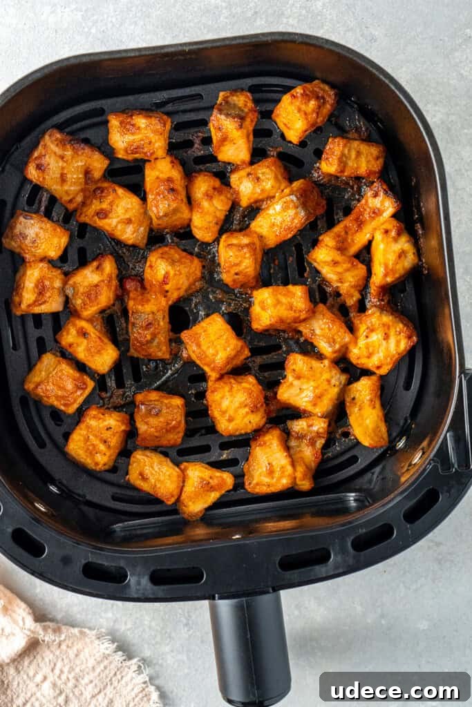 Cooked bang bang salmon in an air fryer basket.