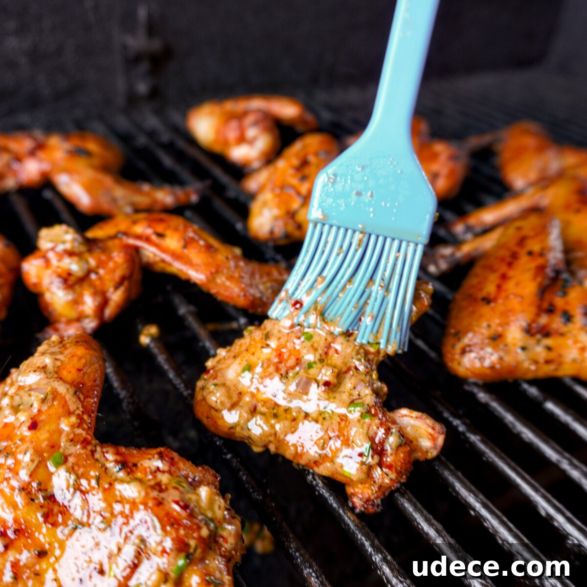cowboy butter sauce being brushed on chicken wings while on the grill.