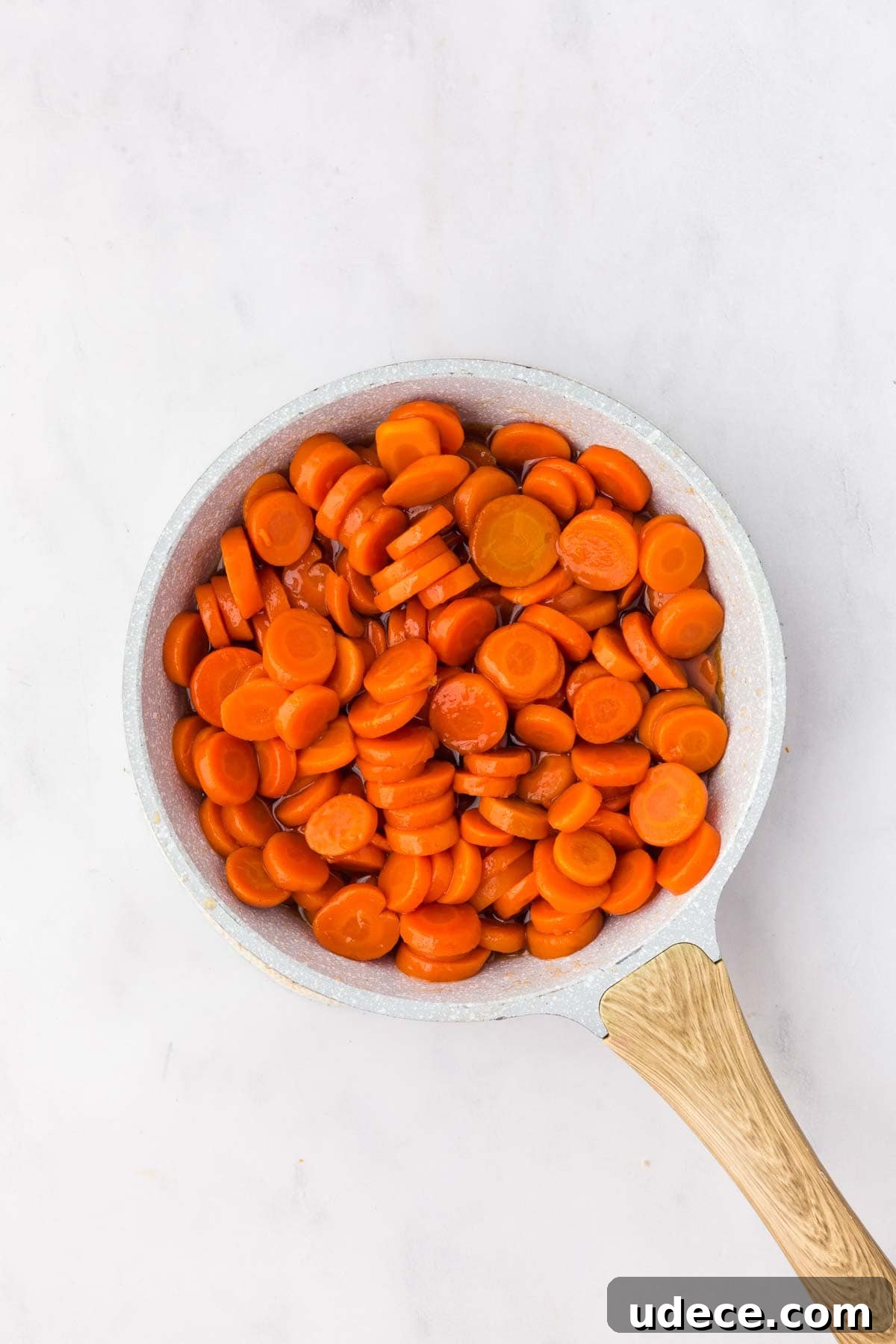 Canned carrot in a skillet coated with brown sugar and honey glaze.