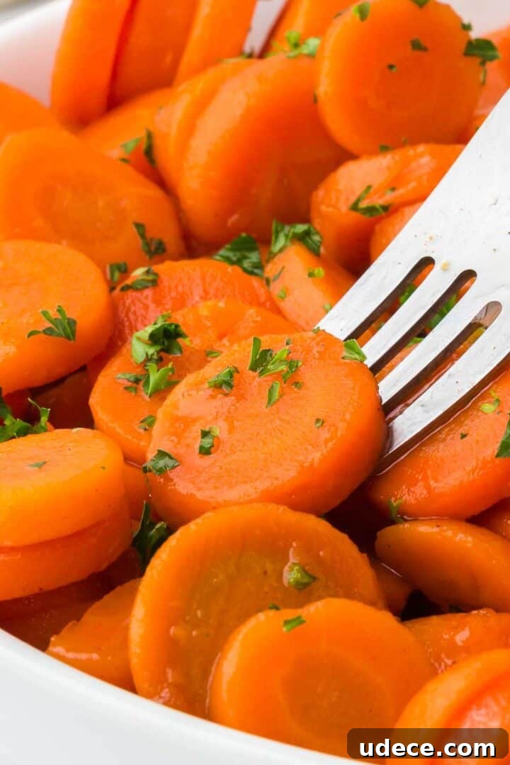 A fork lifting a slice of brown sugar and honey glazed canned carrots.