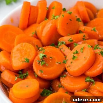 Brown sugar and honey glazed canned carrots, glistening in their syrup and sprinkled with fresh parsley.