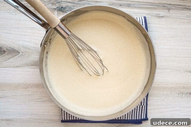Crème Anglaise: Classic French Vanilla Custard Sauce Recipe 5 Custard thickening in a saucepan.
