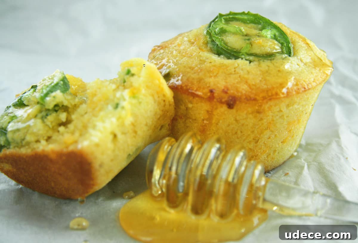 Honey jalapeno cornbread muffins with honey on table.