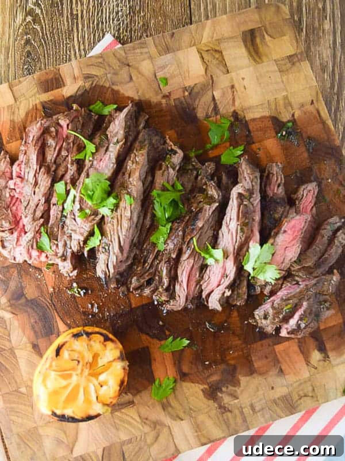 Slices skirt steak on a cutting board topped with cilantro.