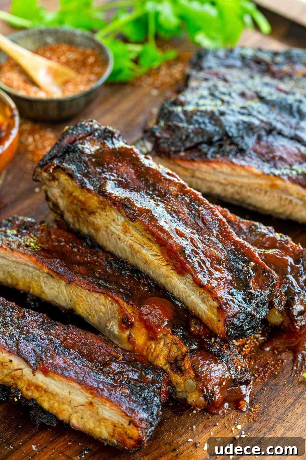 Cut BBQ ribs on a cutting board topped with BBQ sauce.