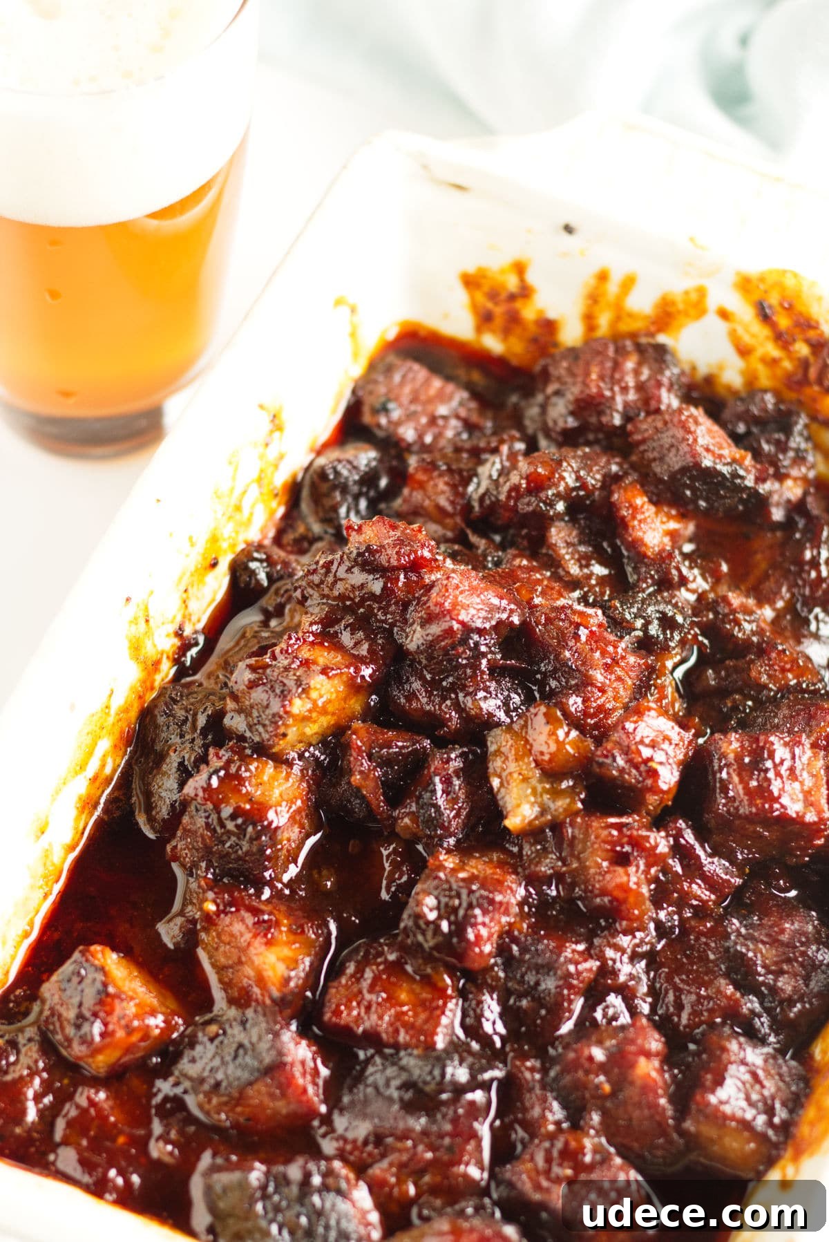 Smoked brisket burnt ends in a Kansas City-style barbecue sauce with a glass of beer.