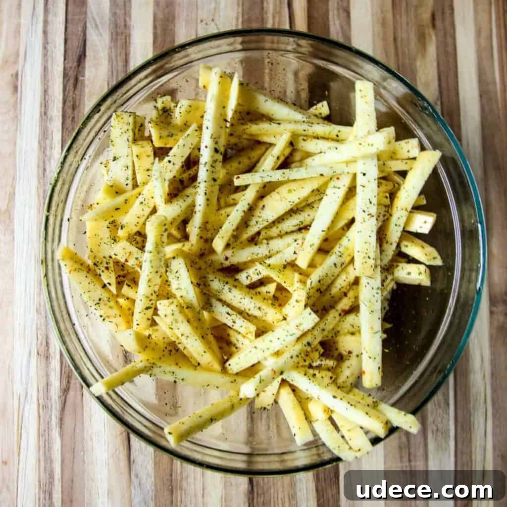 Crispy Air Fryer Rutabaga Fries with Garlic Parmesan Dip 6 Rutabaga fries tossed in a bowl with seasoning.