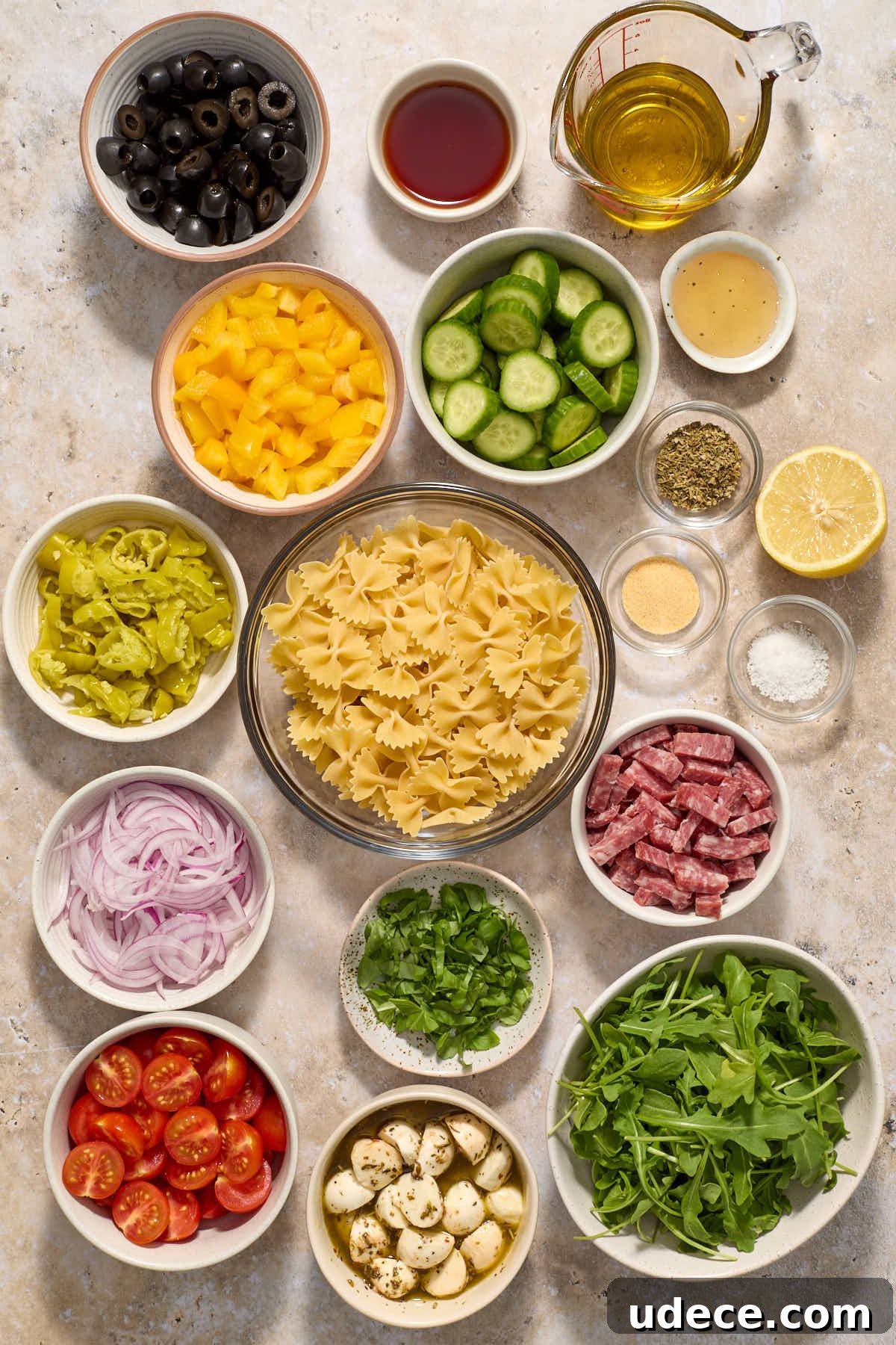 Ingredients to make Italian bow tie pasta salad arranged in individual bowls.