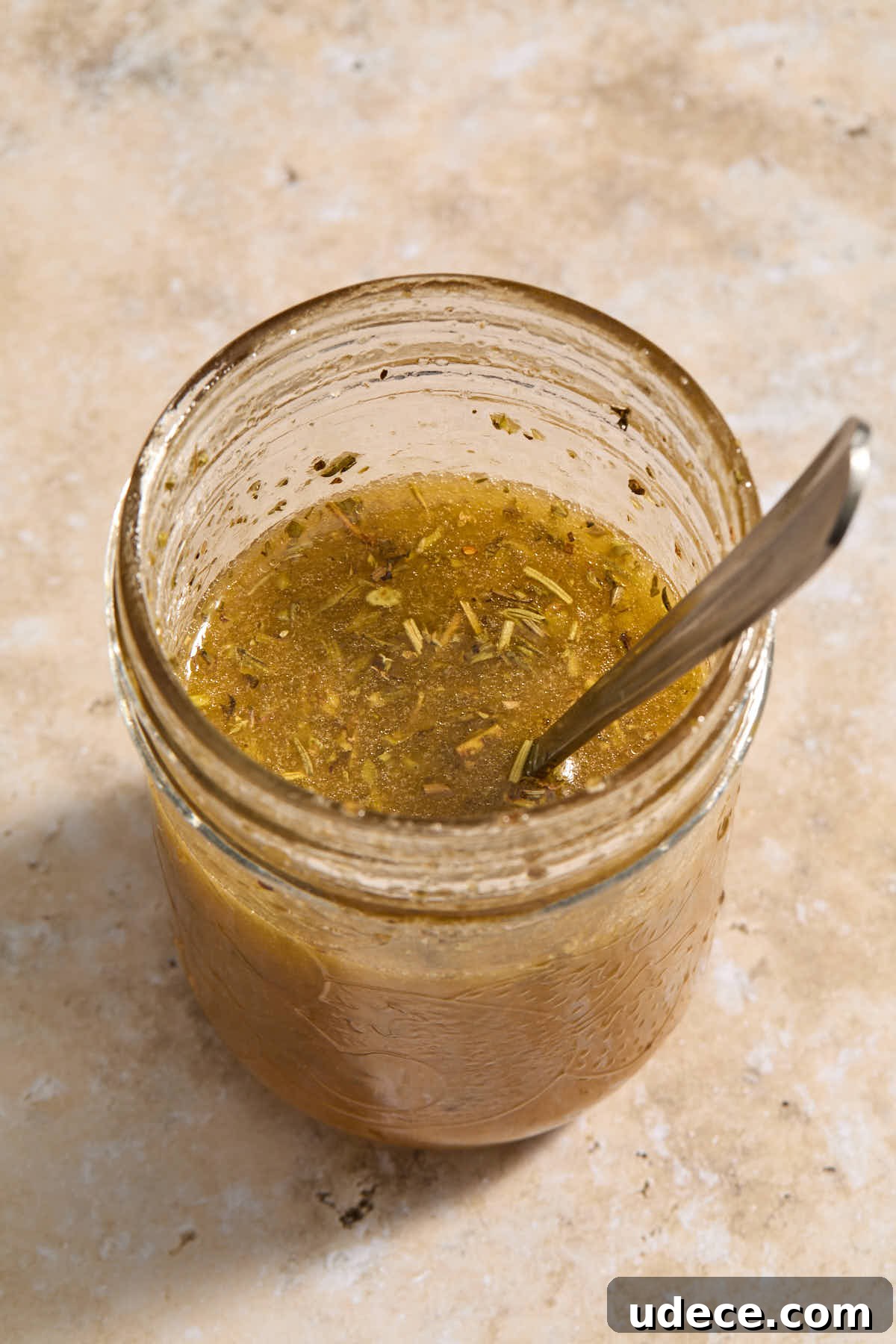 Italian vinaigrette in a glass jar with a spoon.
