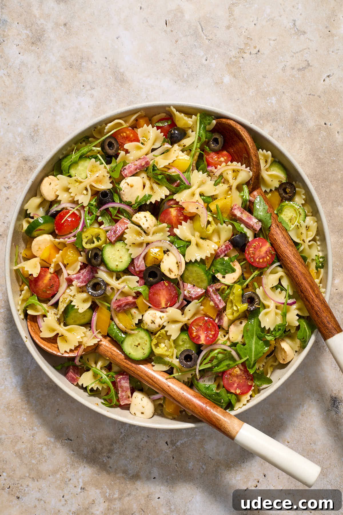Salad and dressing tossed together with wooden salad servers.