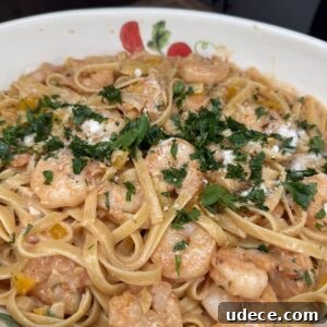 Cajun Shrimp Fettuccine Recipe — Creamy Spicy Pasta in 30 Minutes 28 A bowl of Cajun Shrimp Fettuccine with creamy tomato sauce, yellow bell peppers, and shrimp, garnished with chopped parsley and grated cheese.