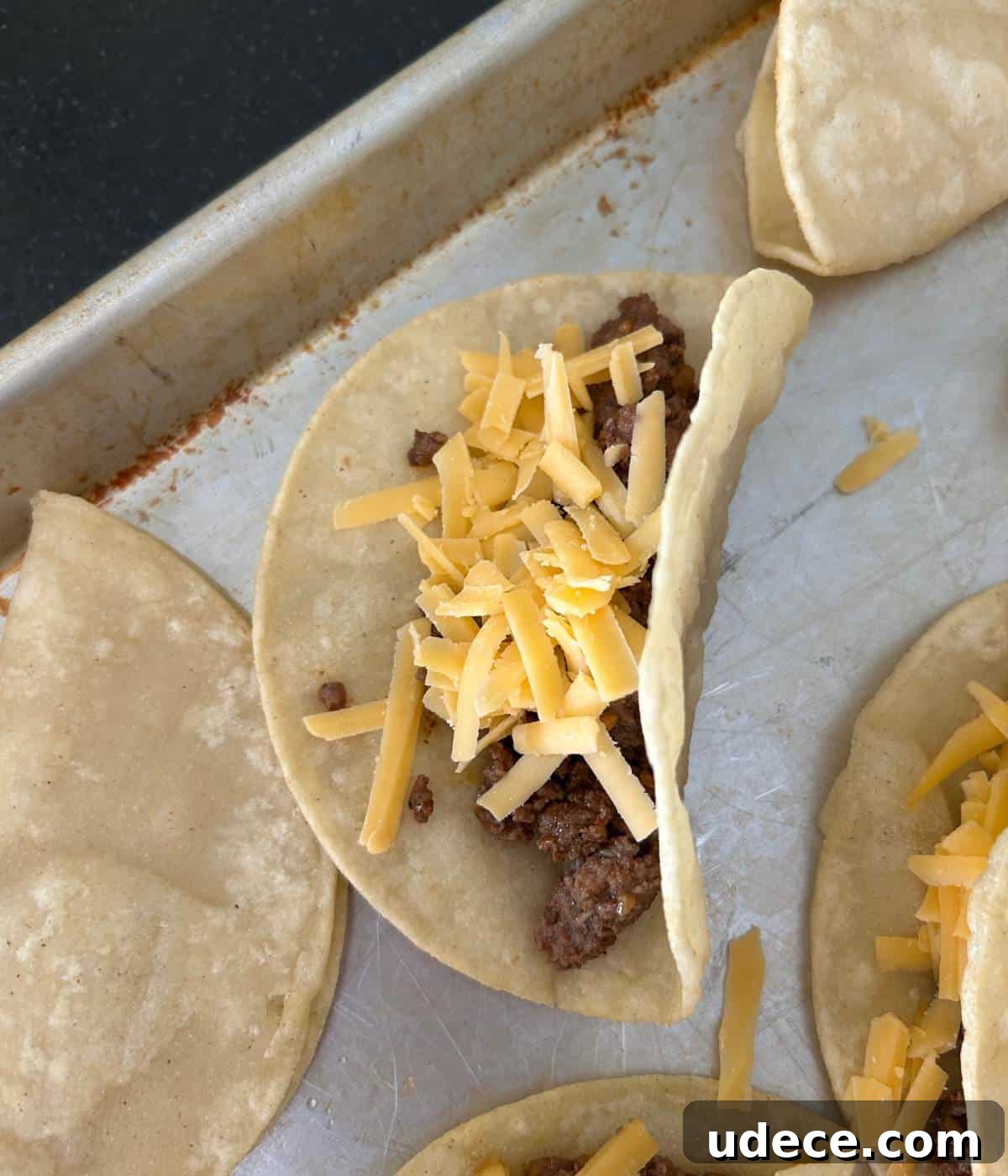 Crispy Ground Beef Tacos Recipe — Quick Weeknight Dinner 7 Assembling the ground beef and cheese in tacos.