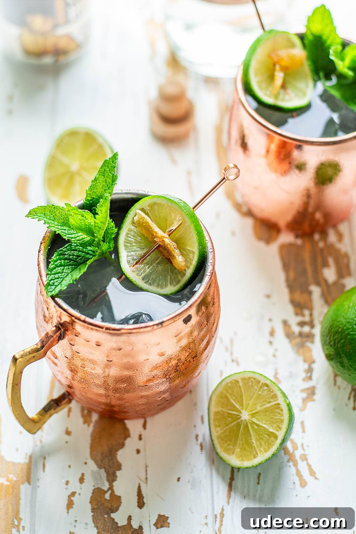 Tequila Mule Cocktail Recipe: How to Make a Classic Mexican Mule 2 Two Tequila Mule cocktails served in copper mugs garnished with mint leaves, a lime wheel, and candied ginger.