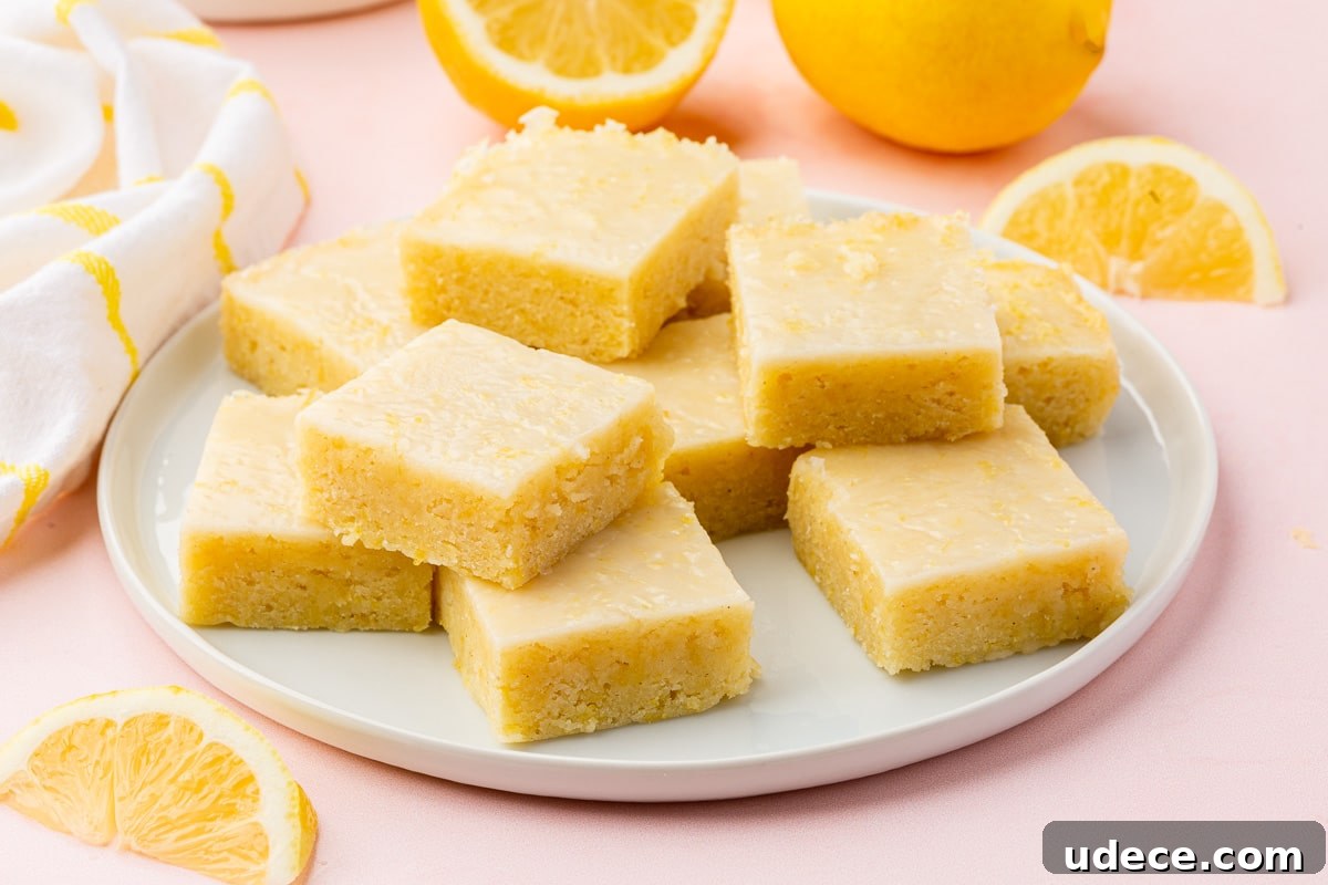 Gluten-Free Lemon Brownies Recipe — Zesty Citrus Brownie Bars 16 A plate of gluten-free lemon brownies that have been stacked with lemon halves and wedges surrounding the plate.
