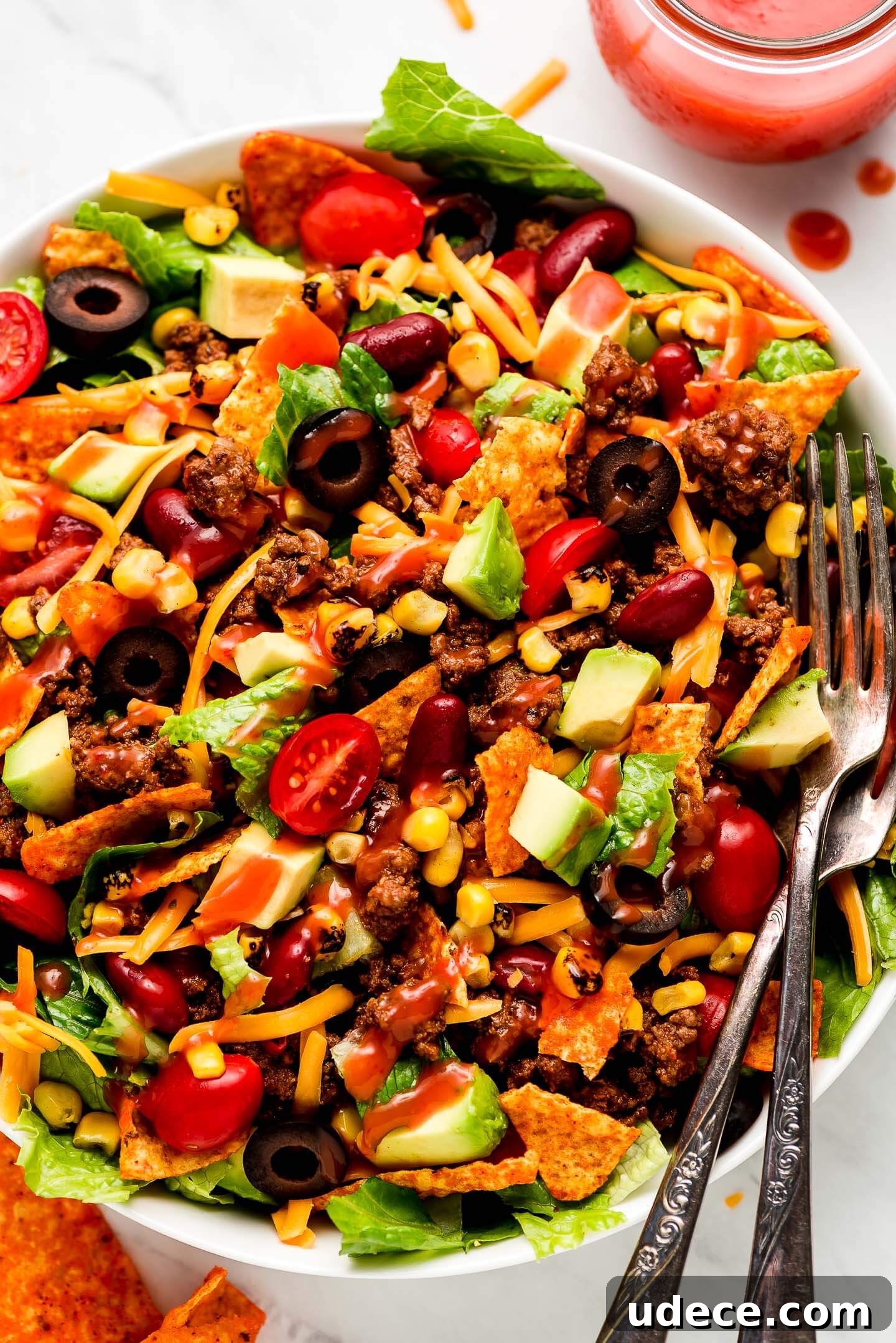 Close up shot of Dorito Taco Salad drizzled with Catalina dressing and two forks in the side.