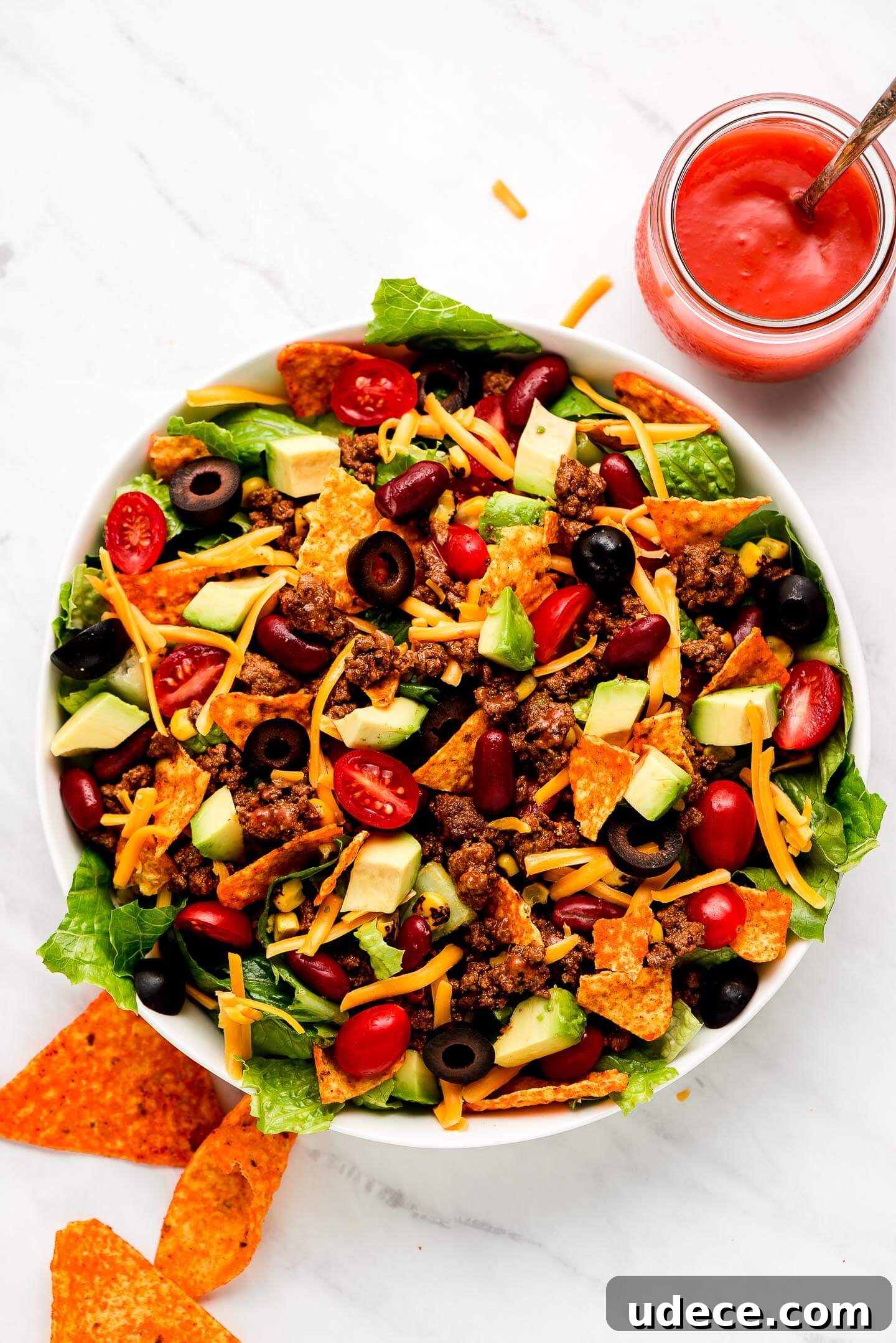 A large bowl full of Dorito Taco Salad with a jar of Catalina dressing to the side.