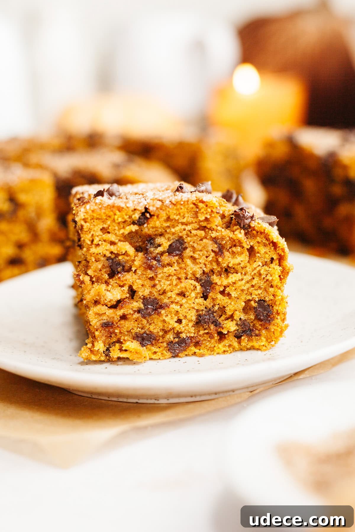 A close up of a square slice of pumpkin chocolate chip cake on a small plate.