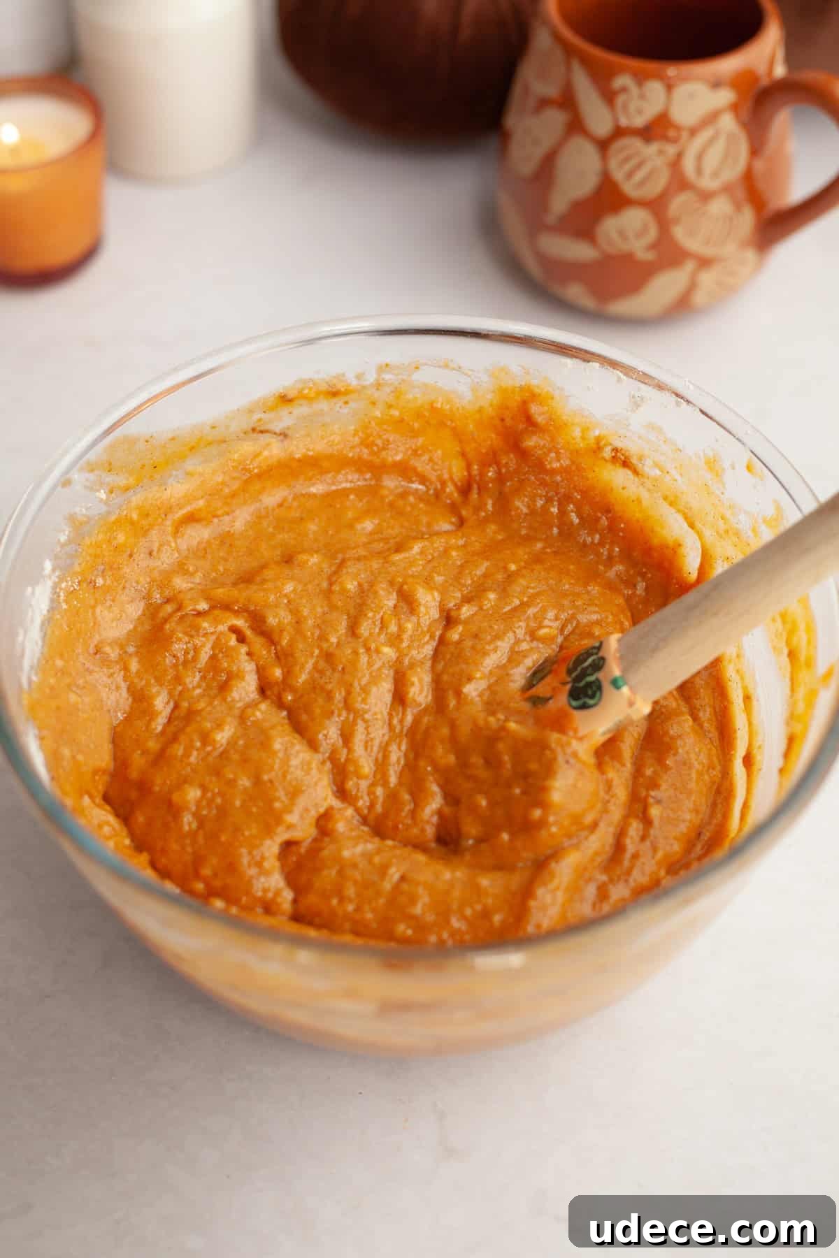 Pumpkin cake batter in a glass bowl with a rubber spatula.
