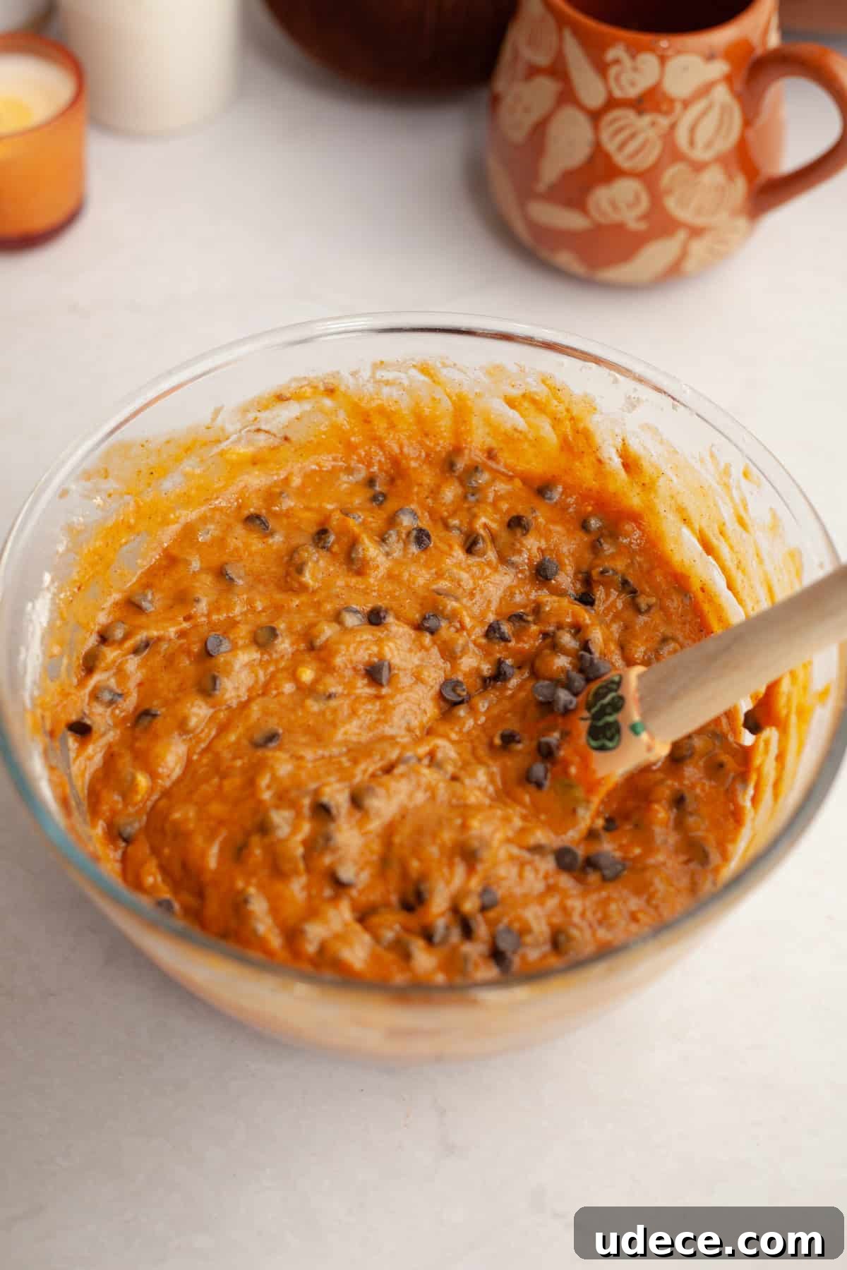 Pumpkin chocolate chip cake batter in a glass bowl with a rubber spatula.
