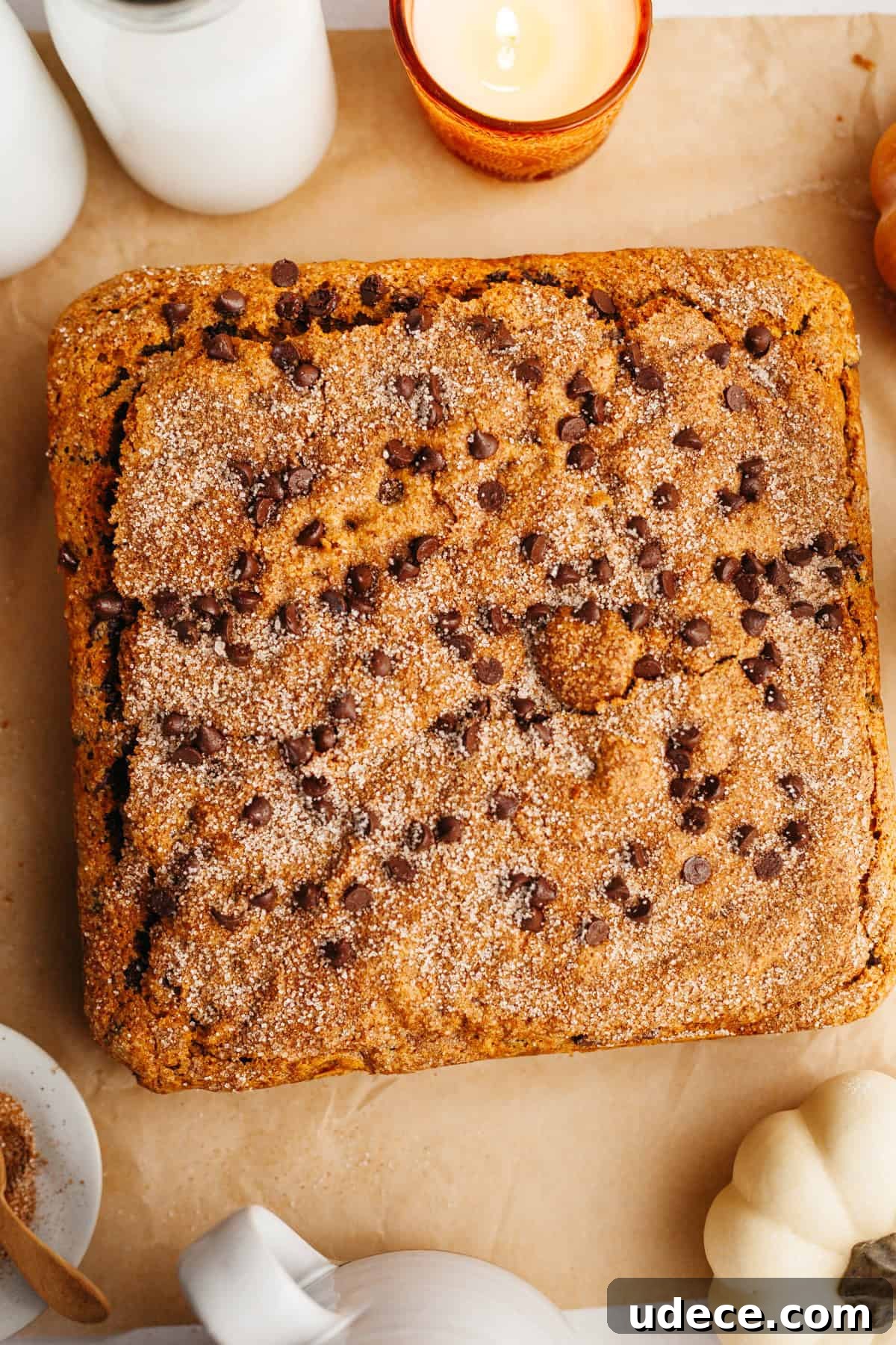 An overhead shot of a square chocolate chip pumpkin cake on parchment paper.