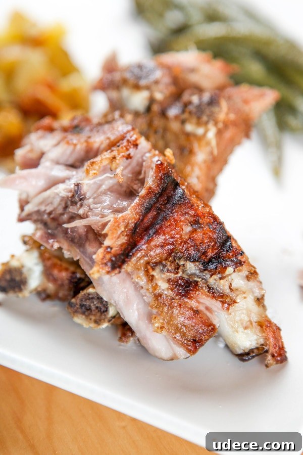 Juicy Instant Pot Ribs: Tender Stovetop-Style BBQ in 45 Minutes 4 a charred rib with dry rub with potatoes and green beans in the background.
