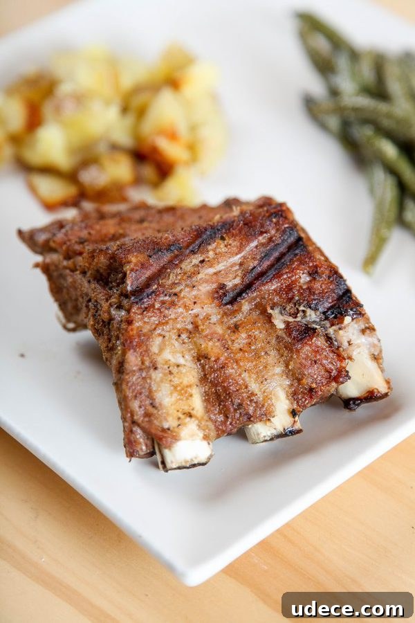 Juicy Instant Pot Ribs: Tender Stovetop-Style BBQ in 45 Minutes 7 3 ribs with dry rub and grill marks on a white plate with potatoes and green beans.