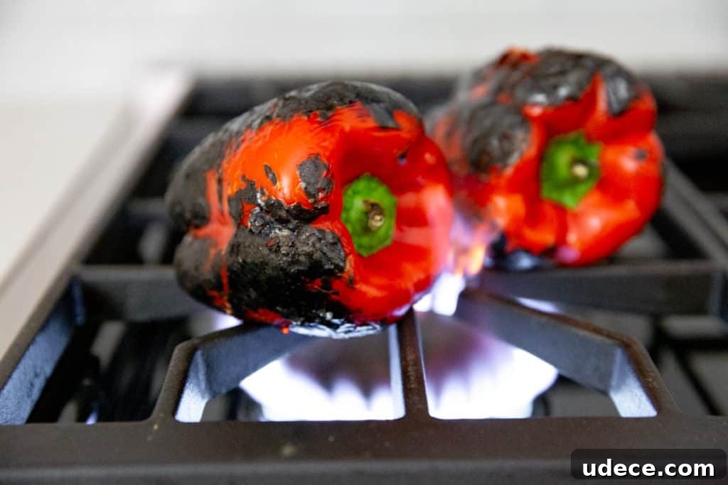 Roasted Red Pepper Pesto Pasta — Gluten-Free Recipe 4 Process shot showing red peppers roasting over a gas flame on a stovetop.