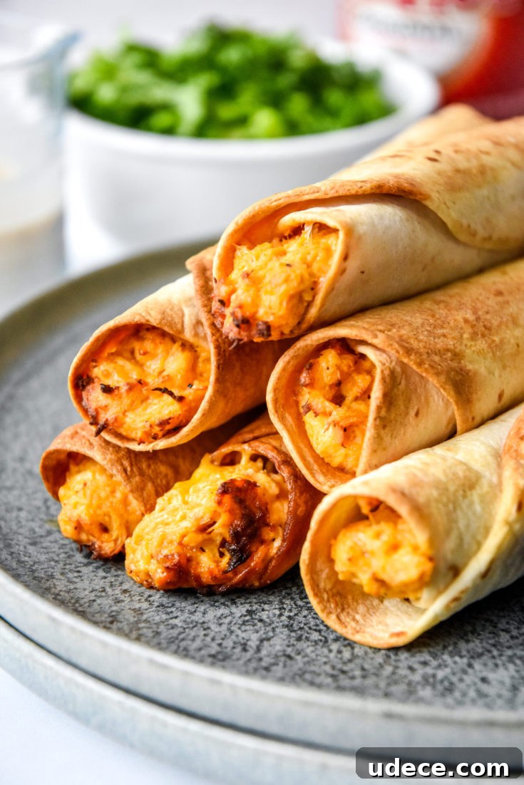 air fryer buffalo chicken flautas cooked and stacked on a plate.