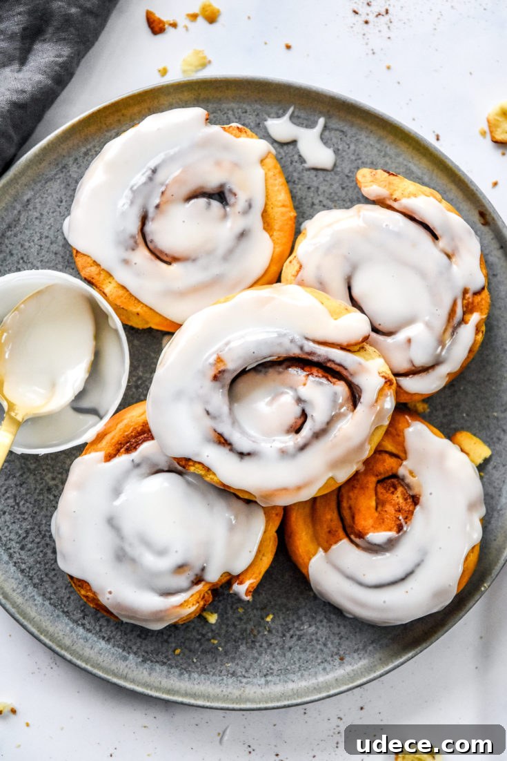 5 air fryer canned cinnamon rolls on a plate with frosting.