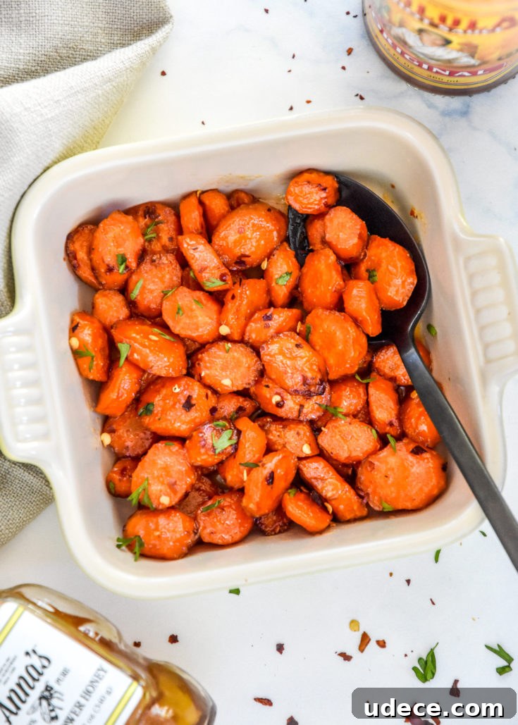 air fryer hot honey glazed carrots in a bowl with a black serving spoon.