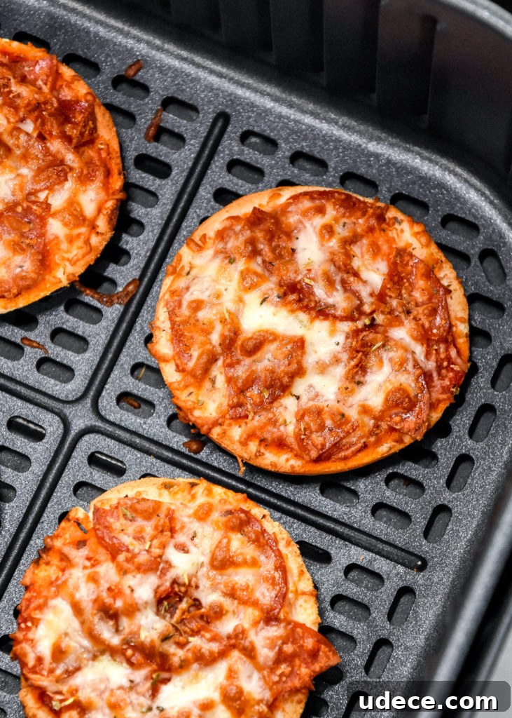 12 Cozy Air Fryer Recipes Perfect for Fall Meals 3 close up of cooked air fryer homemade pizza bagel bites in the air fryer basket.