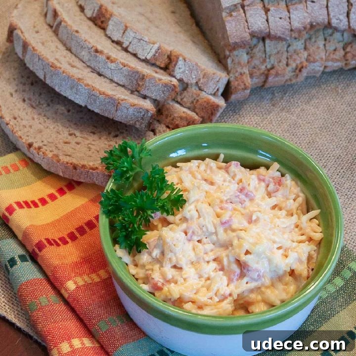 Week 33 Meal Plan for Group 1: Daily Dinner & Prep Guide 4 Homemade Pimento Cheese in a green and white bowl, garnished with a sprig of parsley. There is an unpackaged loaf of sliced bread at the top of the photo.