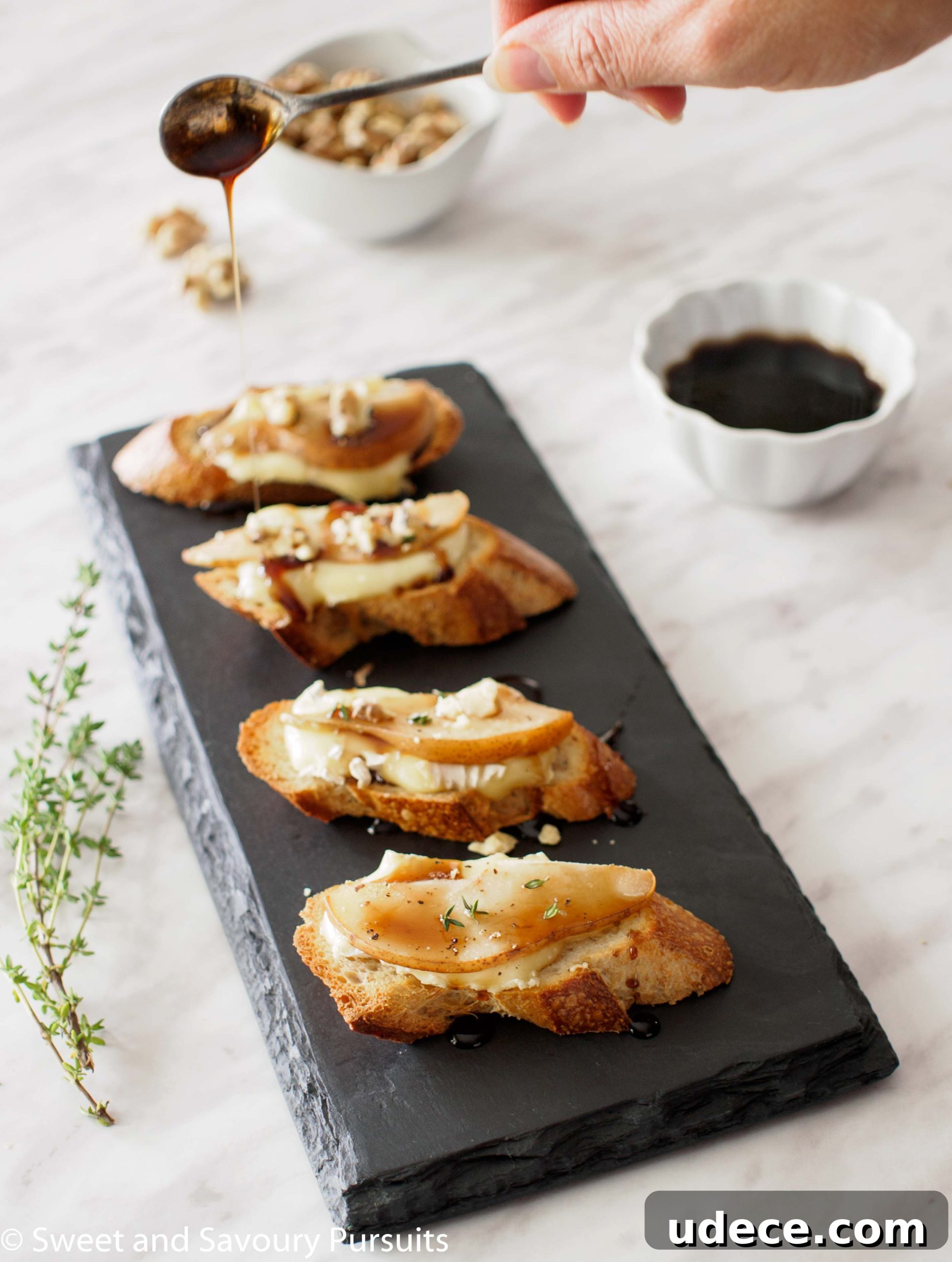 Pear and Brie Crostini topped with balsamic syrup and crumbled walnuts.