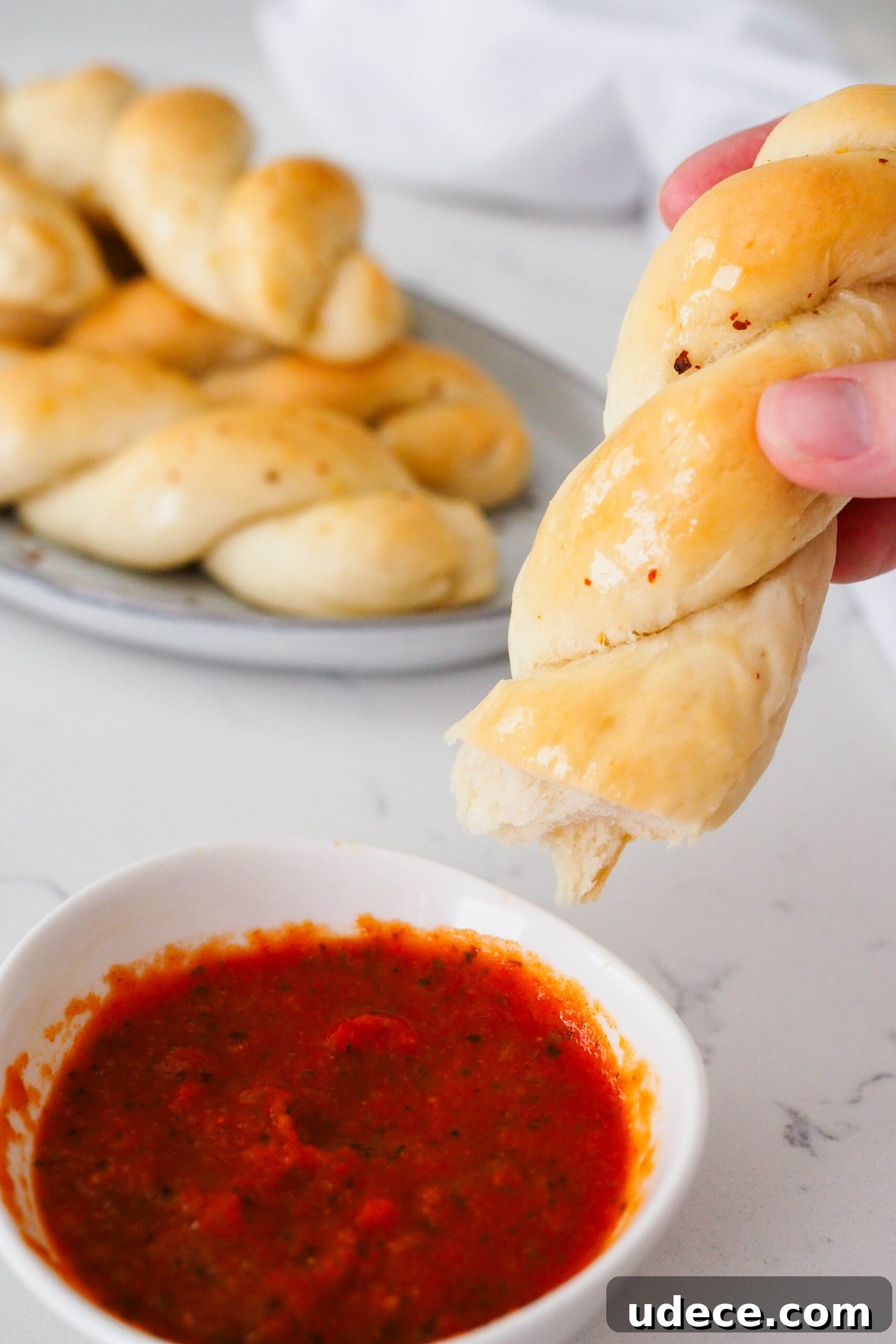Crispy Homemade Garlic Breadsticks with Parmesan and Herbs 2 Half of a twisted garlic breadstick is dipped into marinara sauce.
