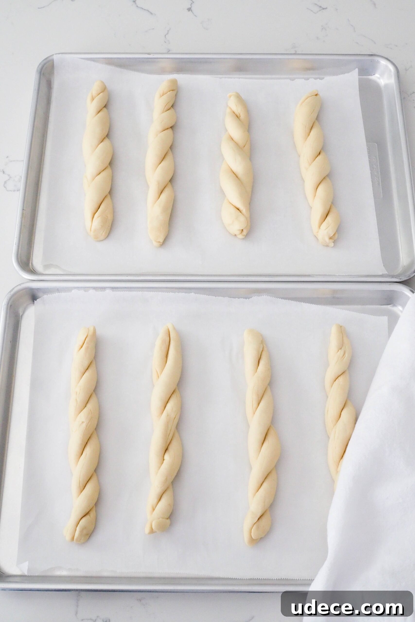 Crispy Homemade Garlic Breadsticks with Parmesan and Herbs 10 Eight twisted garlic breadsticks on a baking sheet.