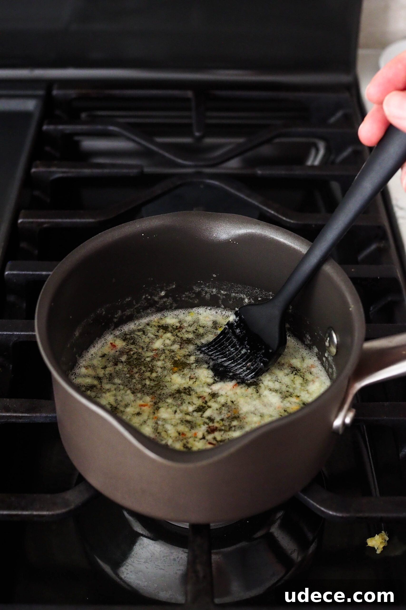 Crispy Homemade Garlic Breadsticks with Parmesan and Herbs 12 A pastry brush stirs garlic into butter in a small saucepan.
