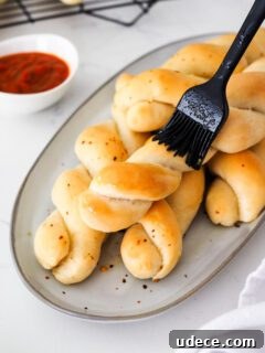 Crispy Homemade Garlic Breadsticks with Parmesan and Herbs 16 A silicone pastry brush brushes garlic butter onto twisted breadsticks.
