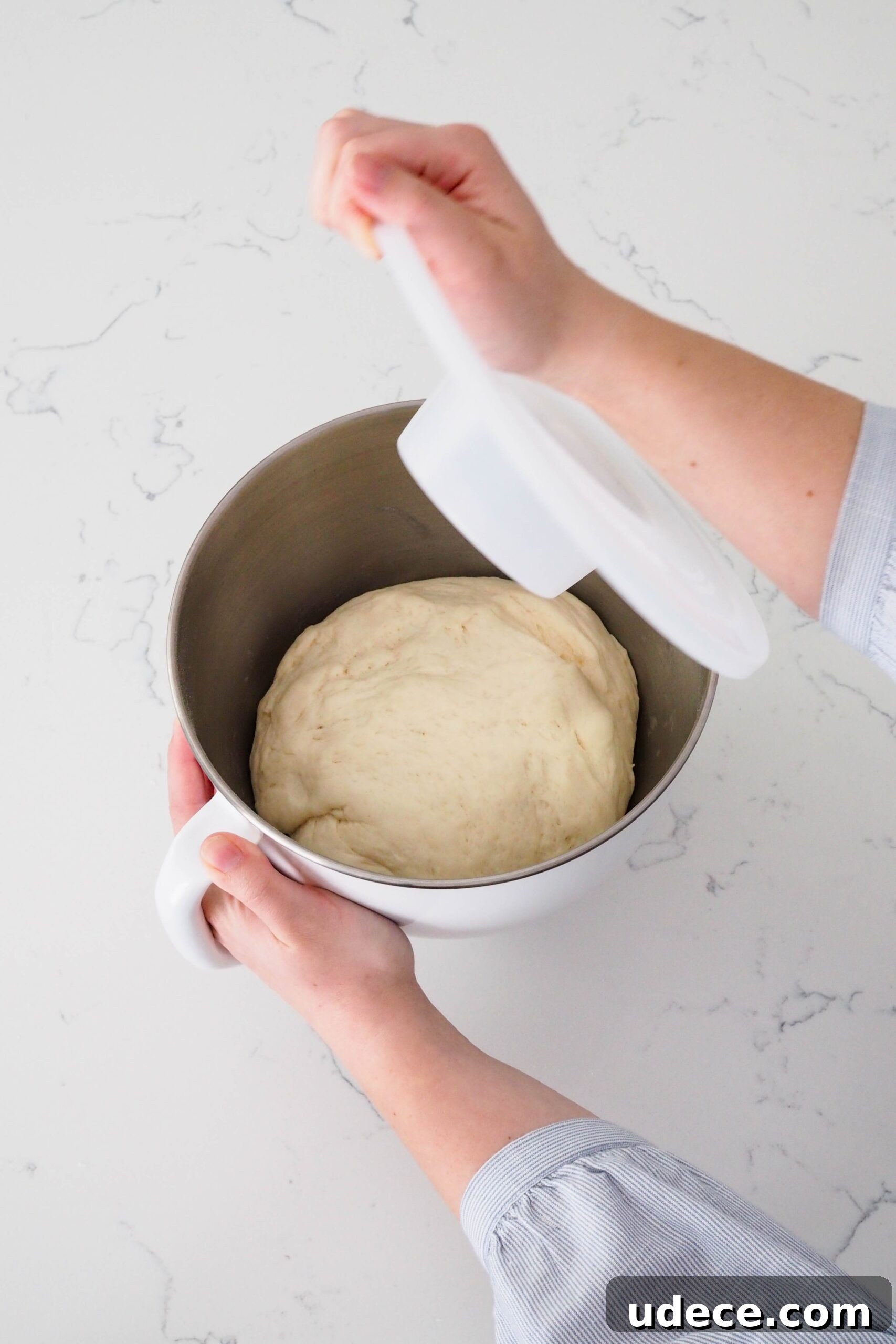 Crispy Homemade Garlic Breadsticks with Parmesan and Herbs 7 A hand removes the lid off of a mixer bowl with enriched dough that has doubled in size.