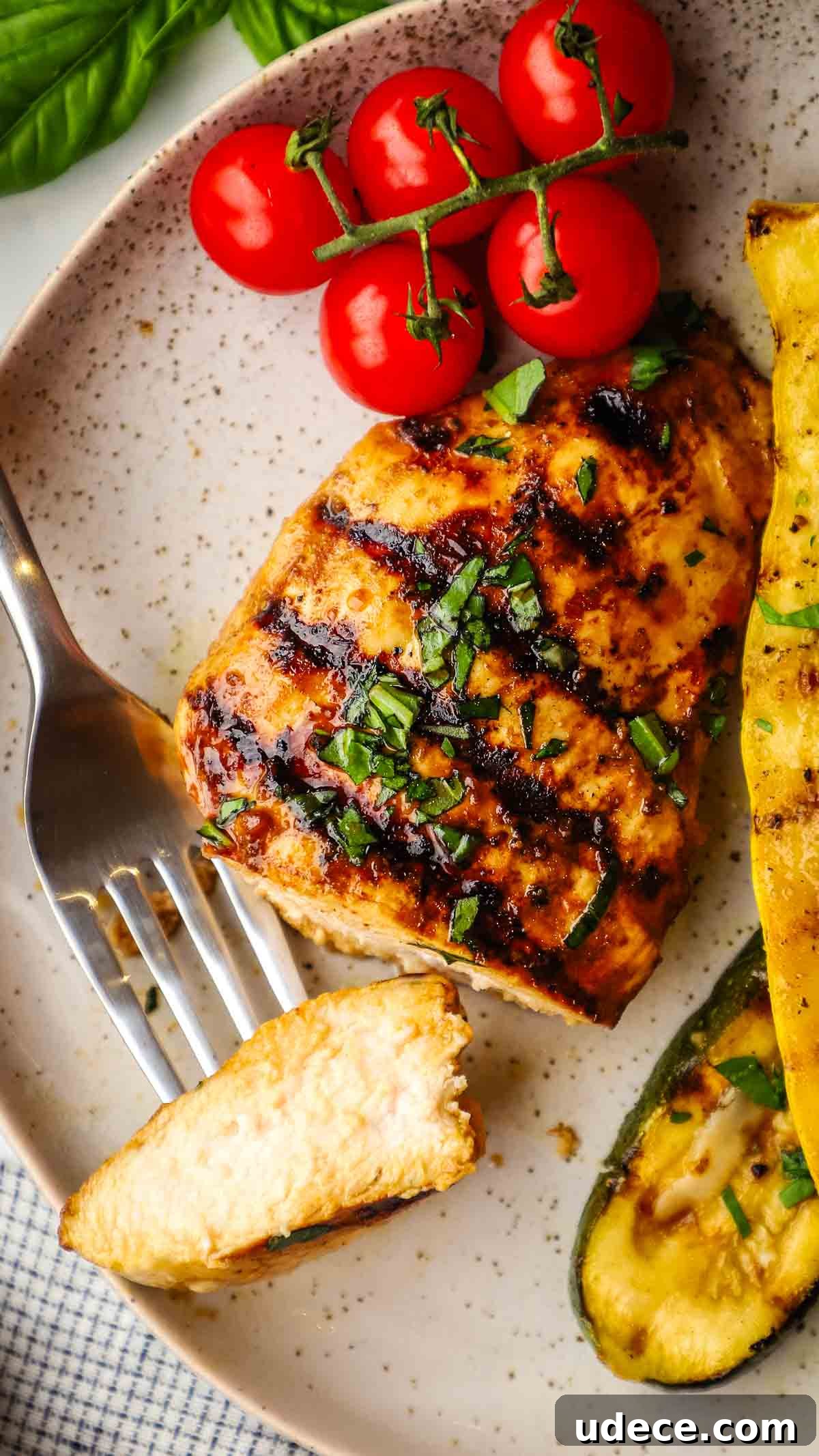 Grilled Balsamic Chicken with Garlic and Rosemary Marinade 11 A grilled chicken breast on a plate with a bite on a fork.