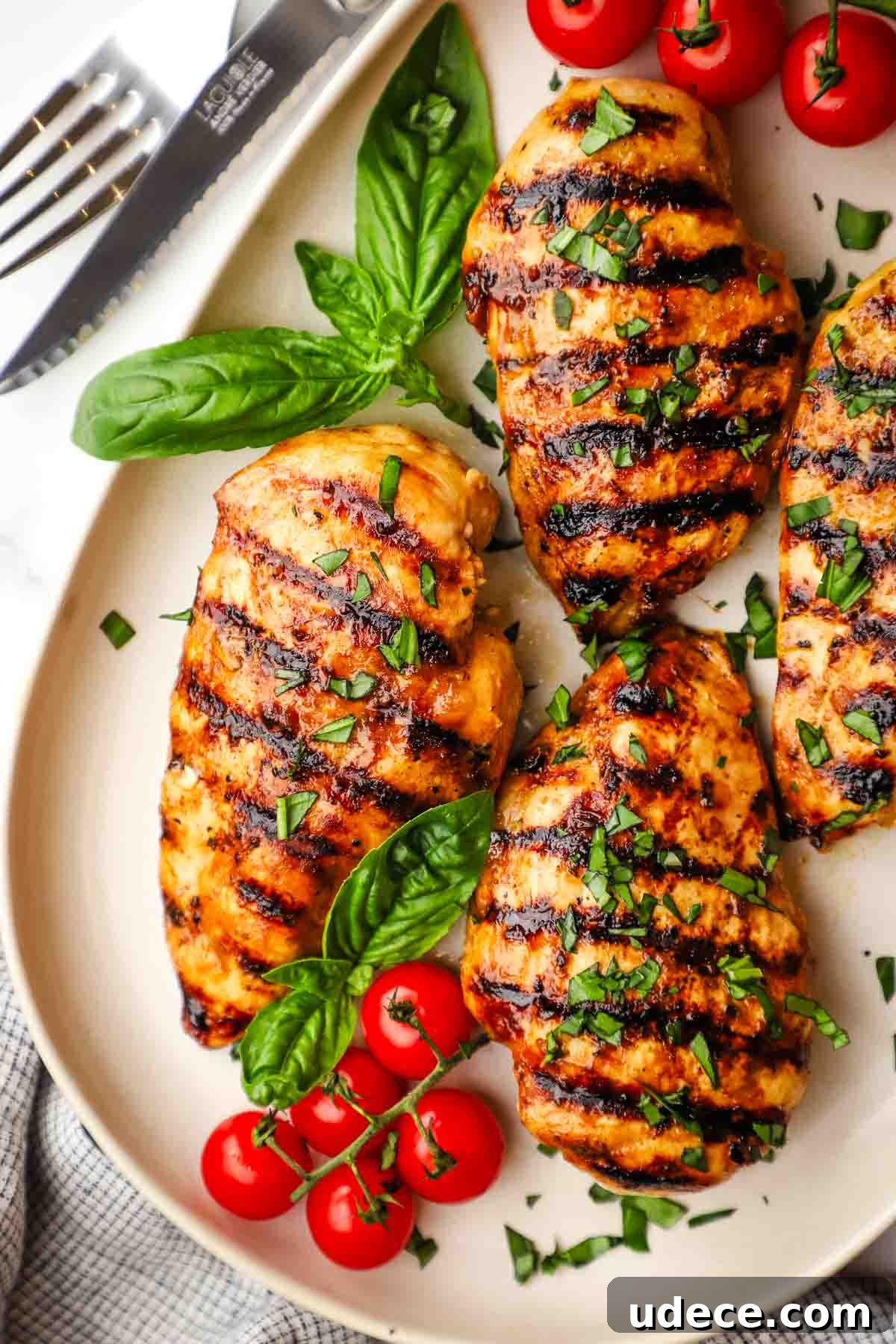 Grilled Balsamic Chicken with Garlic and Rosemary Marinade 9 balsamic grilled chicken breasts on a dish with fresh basil and cherry tomatoes