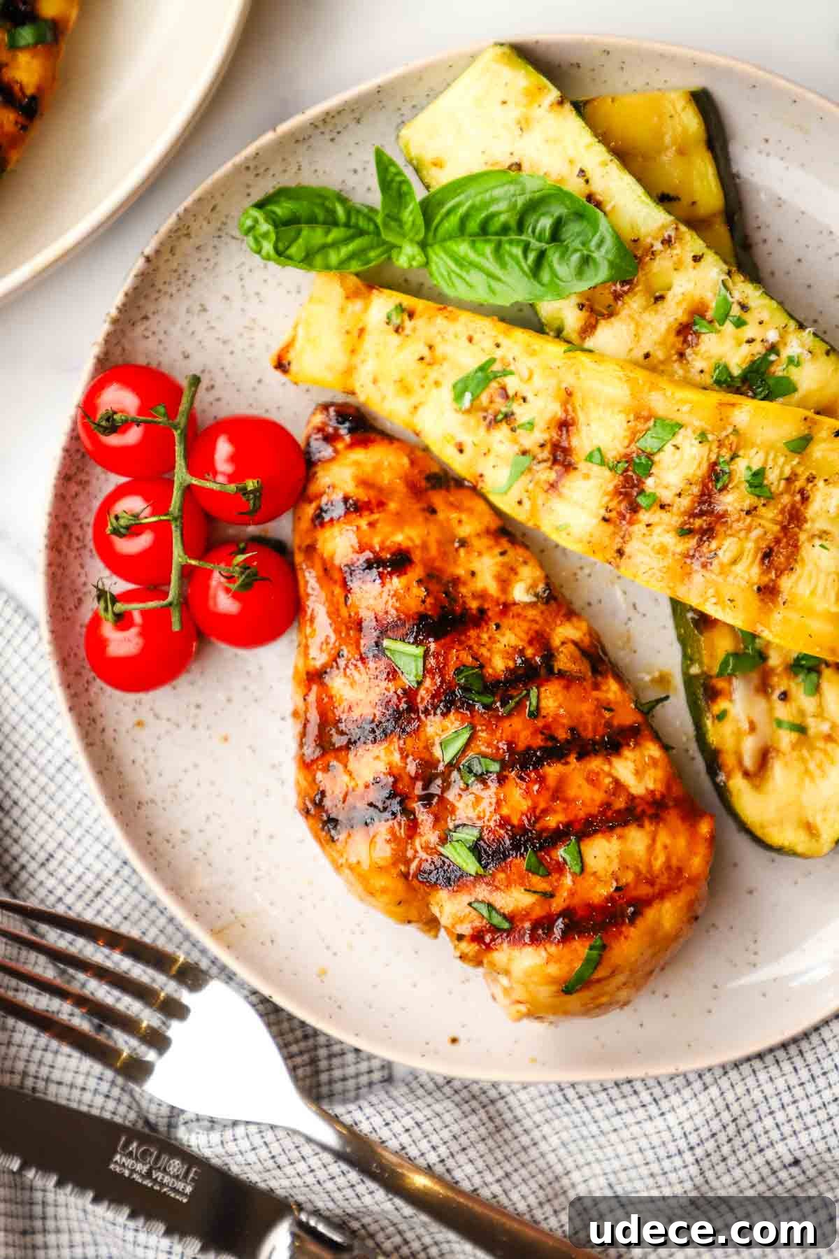 Grilled Balsamic Chicken with Garlic and Rosemary Marinade 10 A grilled chicken breast on a plate with roasted veggies and cherry tomatoes.