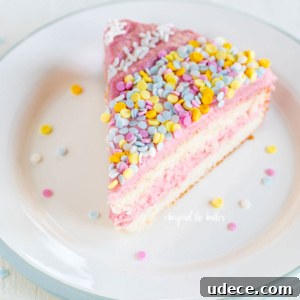 Moist Single-Layer Vanilla Bean Cake Recipe 9 Slice of vanilla bean cake frosted with strawberry swiss meringue buttercream and topped with sprinkles on a dessert plate.