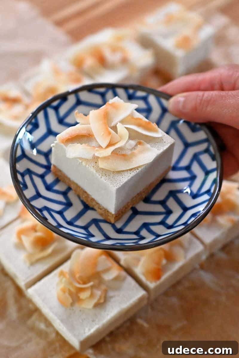 Vegan Coconut Cream Bars — Low-Carb, Gluten-Free Dessert 15 A hand holding a blue and white plate with a coconut cream bar on top.
