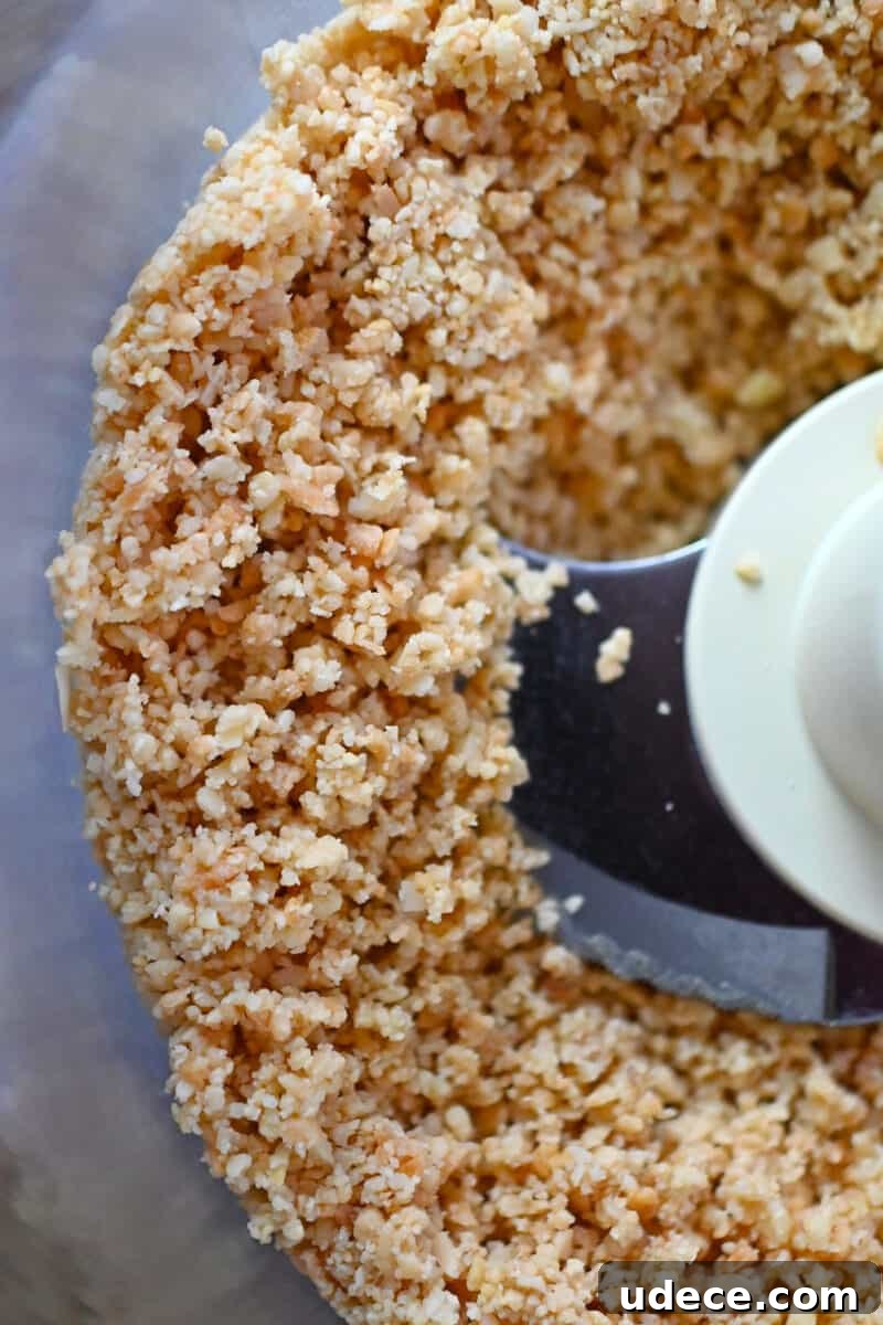 Vegan Coconut Cream Bars — Low-Carb, Gluten-Free Dessert 5 An overhead shot of a food processor filled with chunky almond and coconut flour.