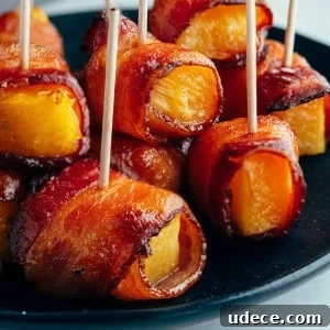Crispy Bacon-Wrapped Pineapple Bites: Sweet and Savory Appetizer 10 Bacon Wrapped Pineapple on a black plate.