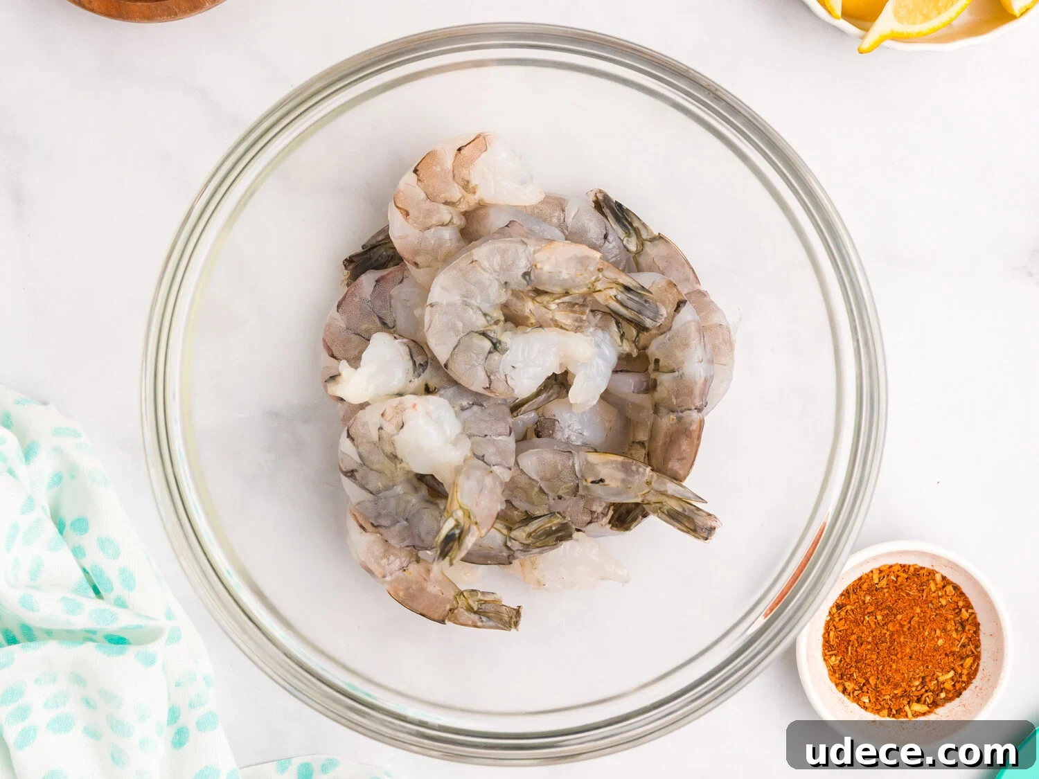 Spicy Cajun Grilled Shrimp Recipe for Quick Weeknight Meals 5 Raw shrimp placed in a clear glass bowl, ready for seasoning, with Cajun spice mix nearby.