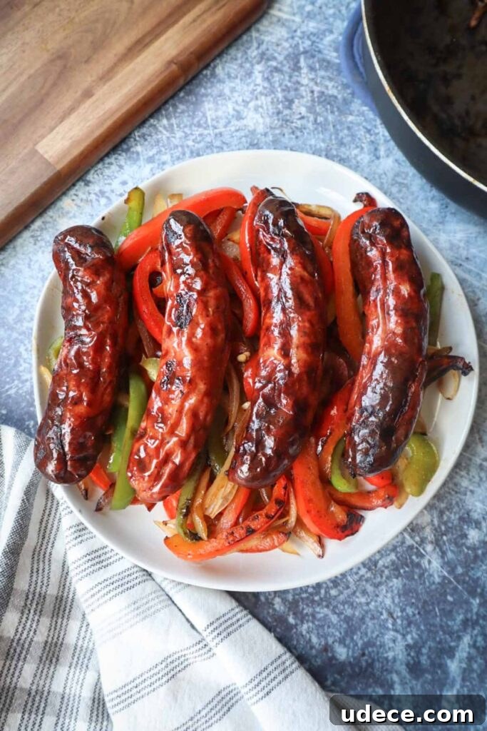 Crispy Air Fryer Chicken Sausage Recipe 2 white plate with four chicken sausages on top of green and red peppers with onion
