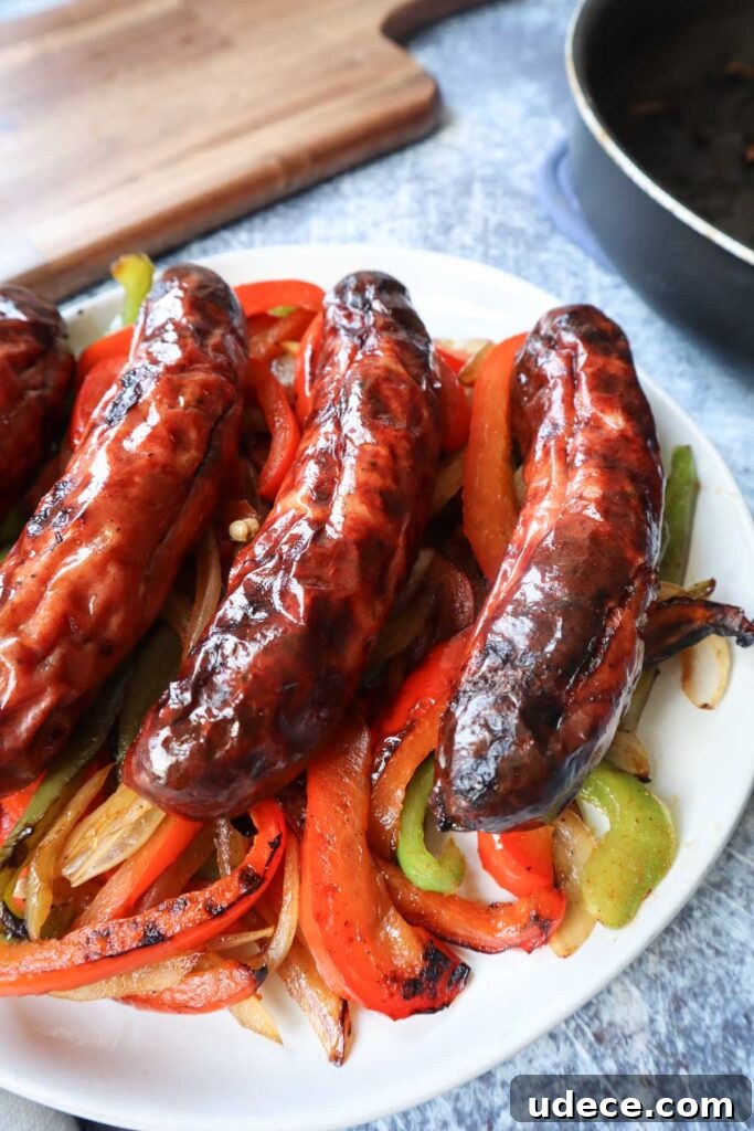 Crispy Air Fryer Chicken Sausage Recipe 6 white plate with four chicken sausages on top of green and red peppers with onion