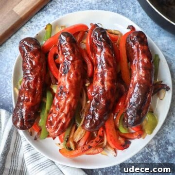 Crispy Air Fryer Chicken Sausage Recipe 7 white plate with four chicken sausages on top of green and red peppers with onion