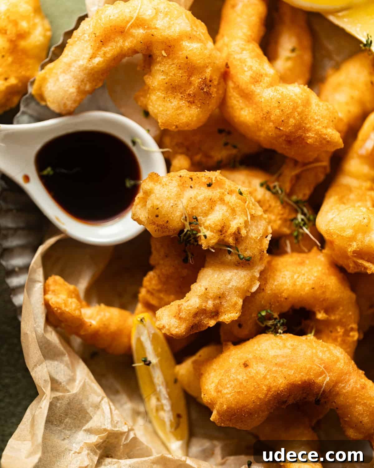 beer battered shrimp on a plate with malt vinegar in a small bowl. 